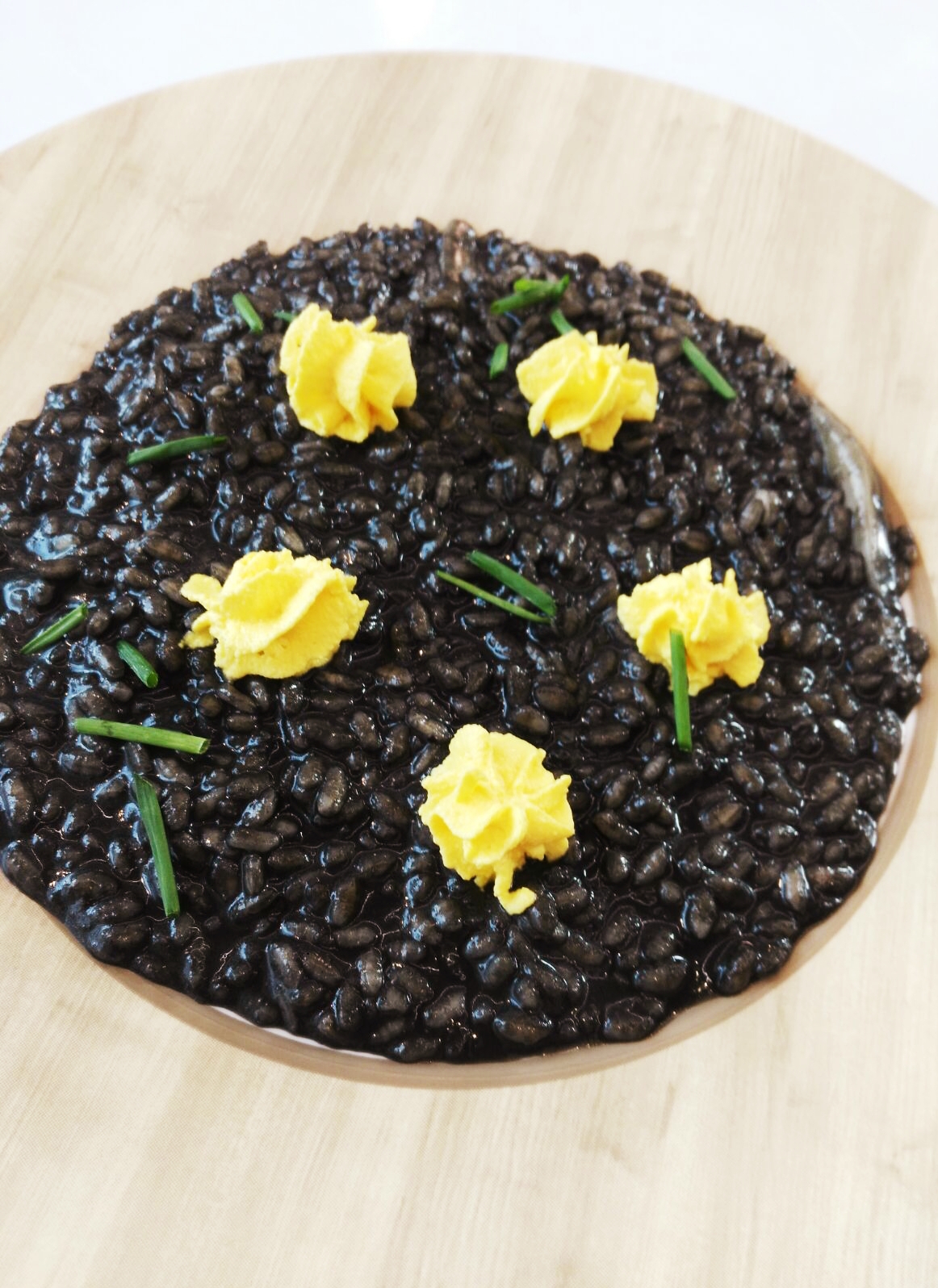 Il risotto al nero di seppia con mousse di zafferano ed erba cipollina, piatto eseguito da Carol Agostini